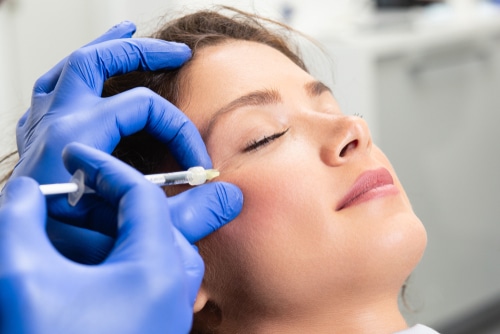 A young woman getting a facial filler with an injection.
