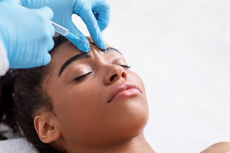A young woman getting Botox injections in her forehead