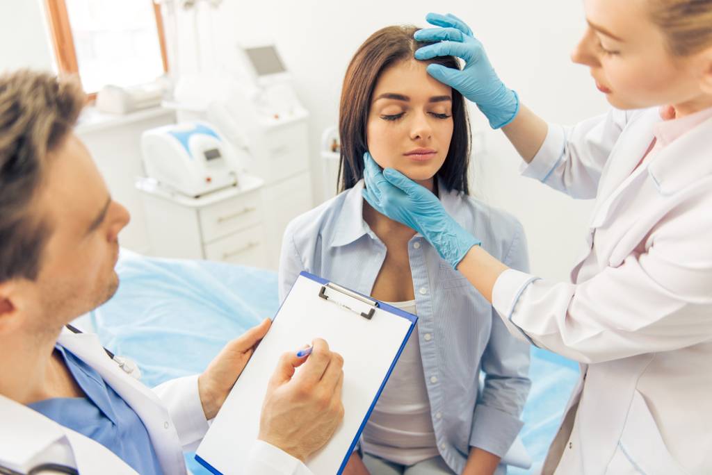 A plastic surgeon evaluating a young woman’s face