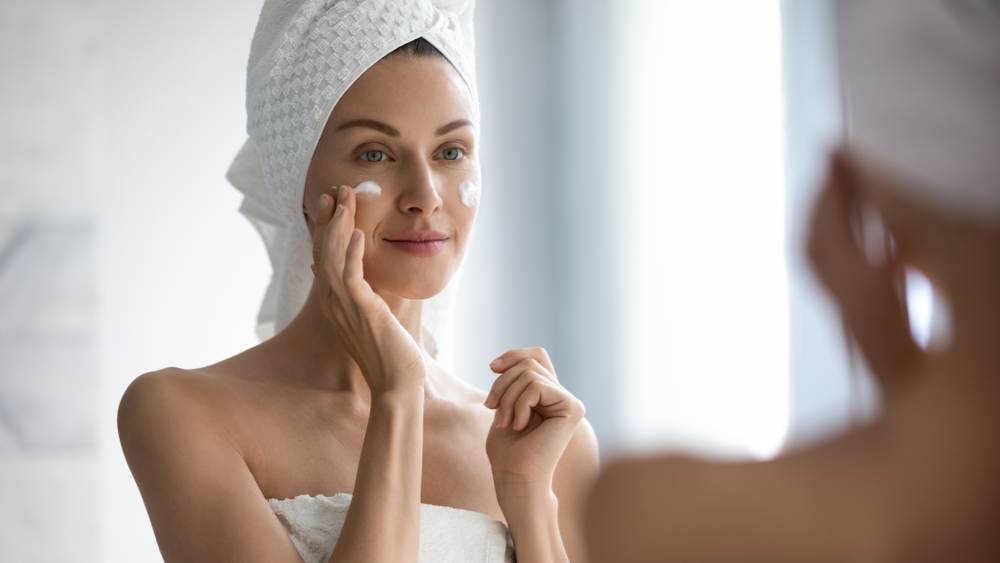 A woman putting on moisturizer