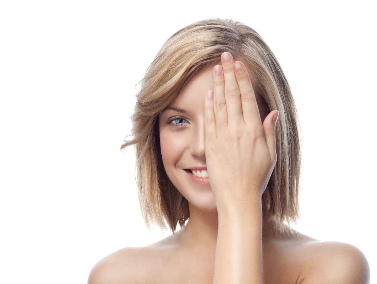 A beautiful young woman covering half of her face with her hand