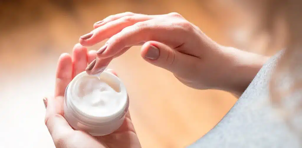 A close up of hands holding a jar of cream