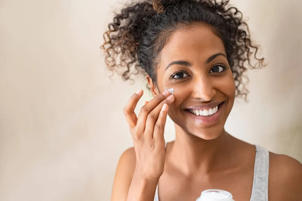 A woman applying cream to her face 