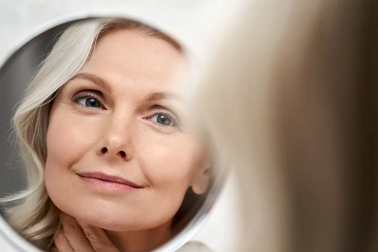 Attractive Woman Looking at Her Face in a Mirror