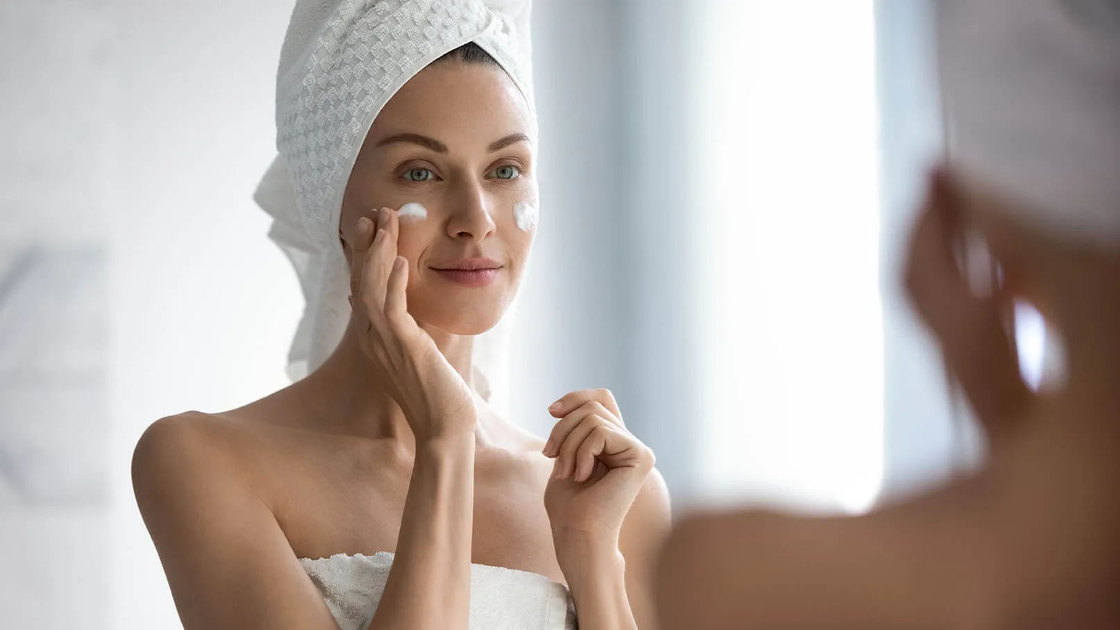 A woman applying cream to her face